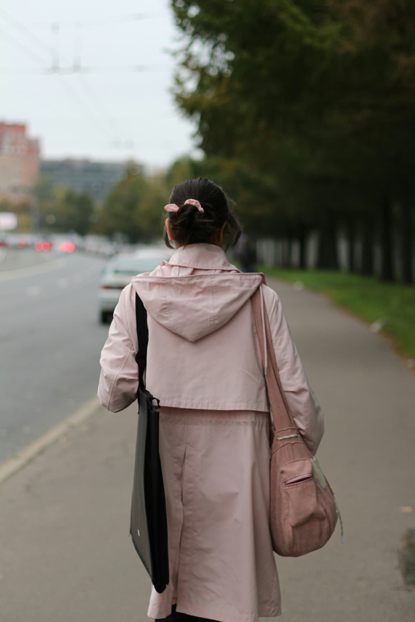person strolling through a city square with a bright tote bag and sunlight