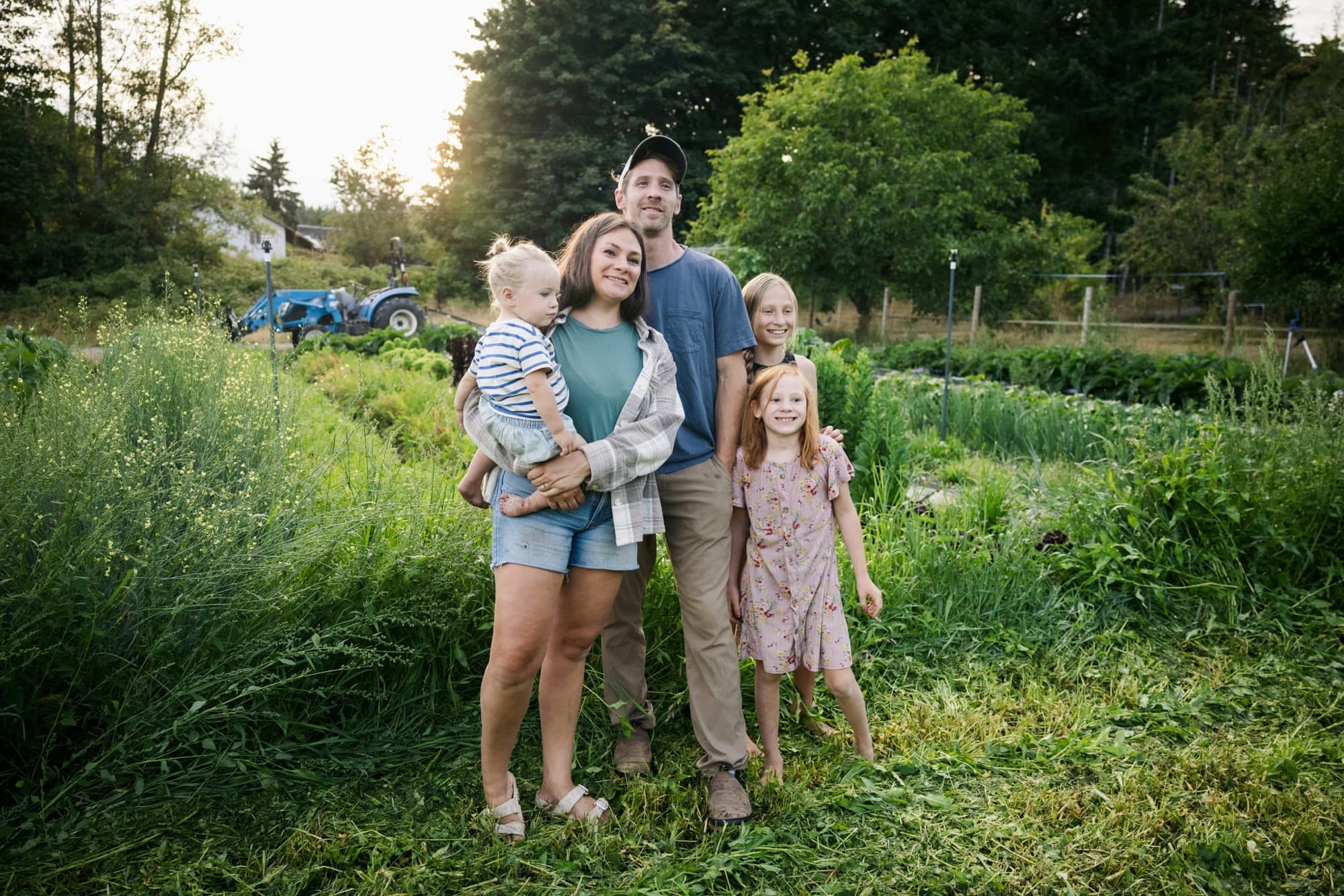 family smiling together in a lush community garden at sunset